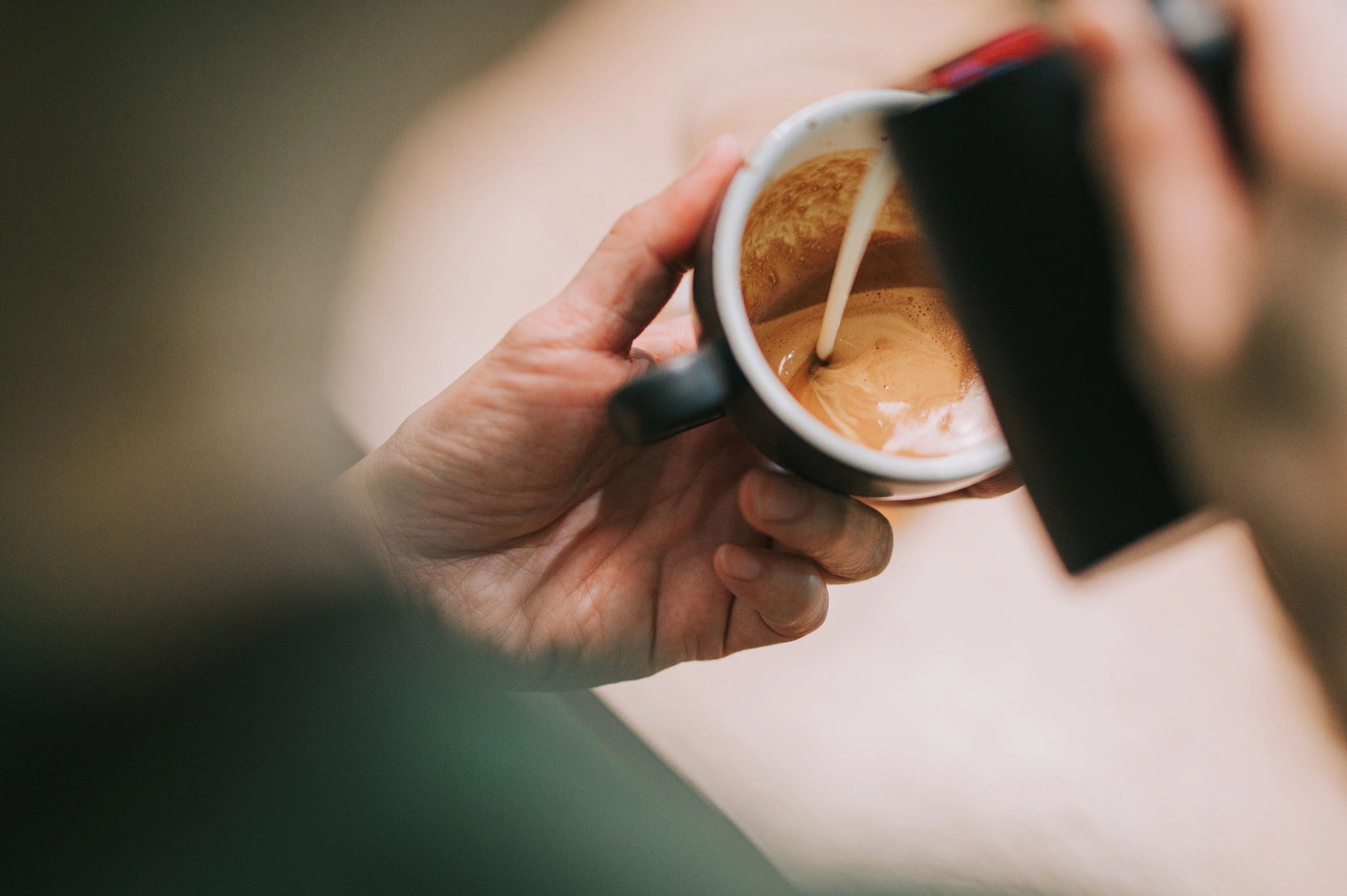 Barista pouring milk into coffee to create latte art