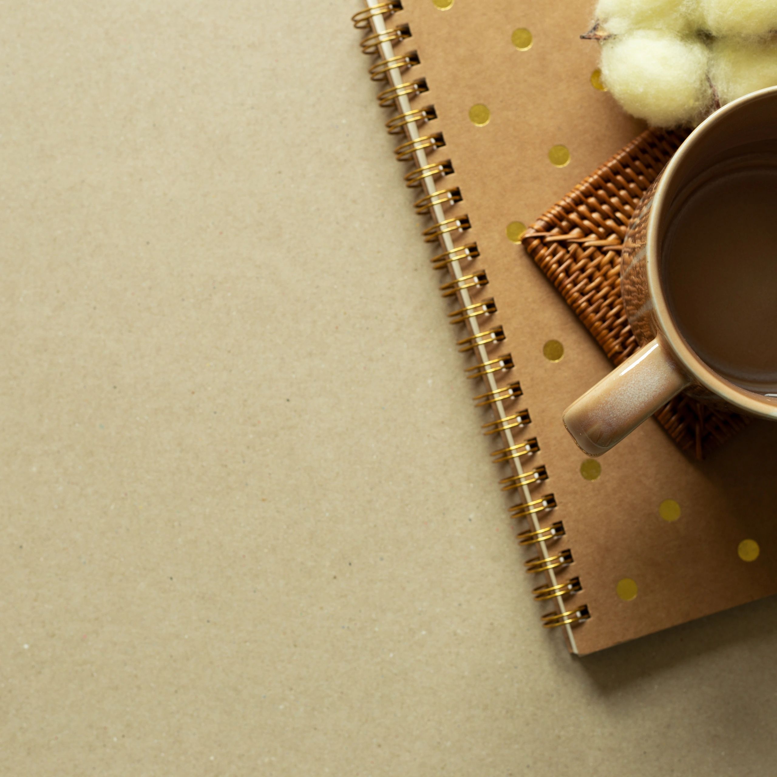 Notebook, mug cup, cotton plant on brown background. autumn and winter concept. flat lay, top view, copy space