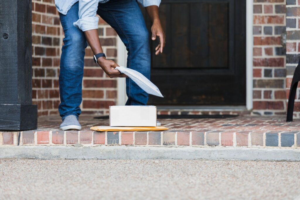 Unrecognizable man picks up packages on doorstep