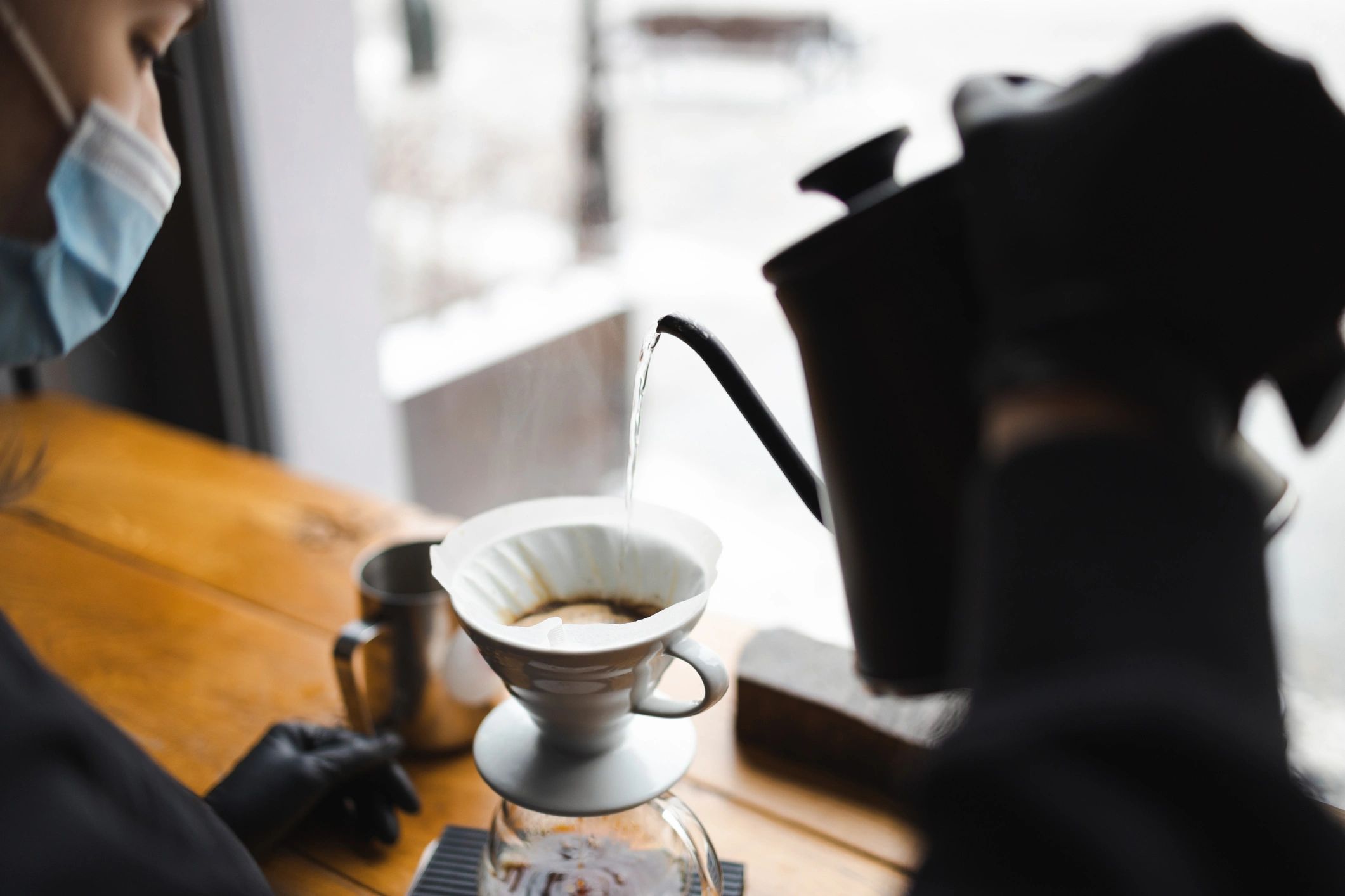 Barista pouring hot water for pour-over coffee in a modern cafe
