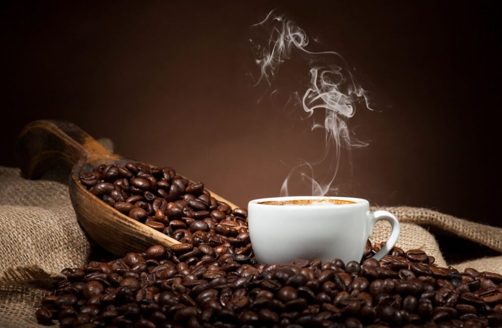 Hot cup of coffee on table with whole beans